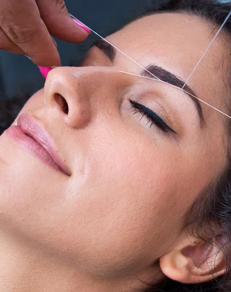 Professional eyebrow threading for precise brow shaping and facial hair removal at a salon.